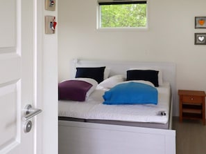 A bedroom with a bed, a nightstand, a window, and a door. - 6 Person Holiday Home in Degeberga (Degeberga)