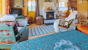 L'intérieur d'un chalet confortable, avec une cheminée, des meubles à motifs écossais et un tapis bleu à motifs.