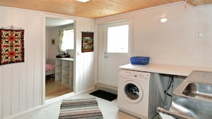 A laundry room with a washing machine, a sink, and a blue basket on a countertop. - 9 Person Holiday Home in Fister (Hjelmeland)
