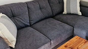 A sectional sofa with a dark fabric, two pillows with striped patterns, and a wooden coffee table.