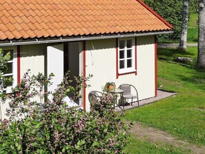 Une maison de plain-pied avec un toit en tuiles, une porte d’entrée et un petit patio comprenant une table et deux chaises.