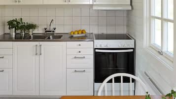 A kitchen with white cabinets, a stainless steel sink, a stove, and a window.