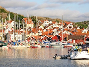 A harbor with multiple boats and a row of houses with red roofs. - 5 Person Holiday Home in Hunnebostrand (Hunnebostrand)