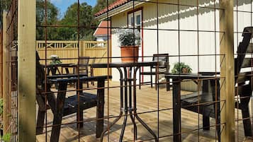 A wooden deck with metal railings, outdoor furniture, and a potted plant.