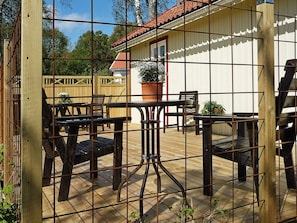 A wooden deck with metal railings, outdoor furniture, and a potted plant. - 5 Person Holiday Home in Hunnebostrand (Hunnebostrand)