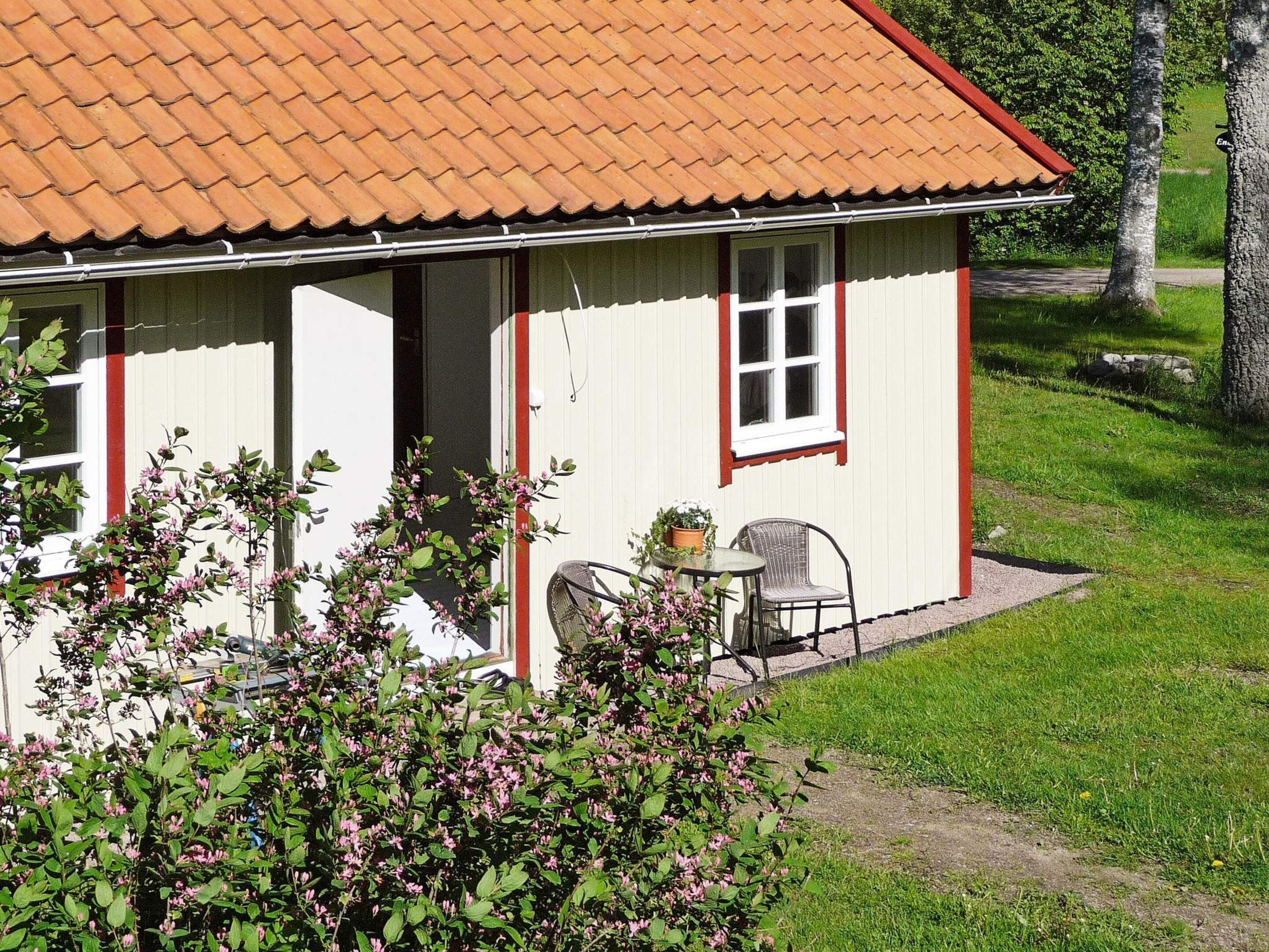 A single-story house with a tiled roof, a front door, and a small patio area with a table and two chairs.