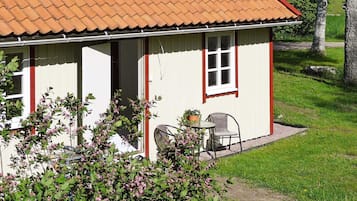 A single-story house with a tiled roof, a front door, and a small patio area with a table and two chairs.