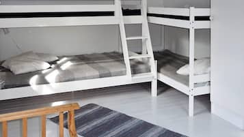 A bunk bed room with a wooden ladder, a small table, and a striped rug.