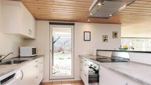 A modern kitchen with white cabinets, a microwave, a stove, and a sink. - 5 Star Holiday Home in Hals (Asaa)