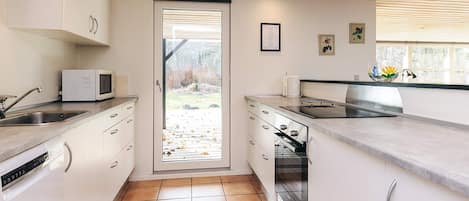A modern kitchen with white cabinets, a microwave, a stove, and a sink.
