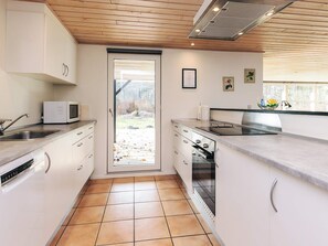 Una cocina moderna con armarios blancos, un microondas, una estufa y un lavamanos.