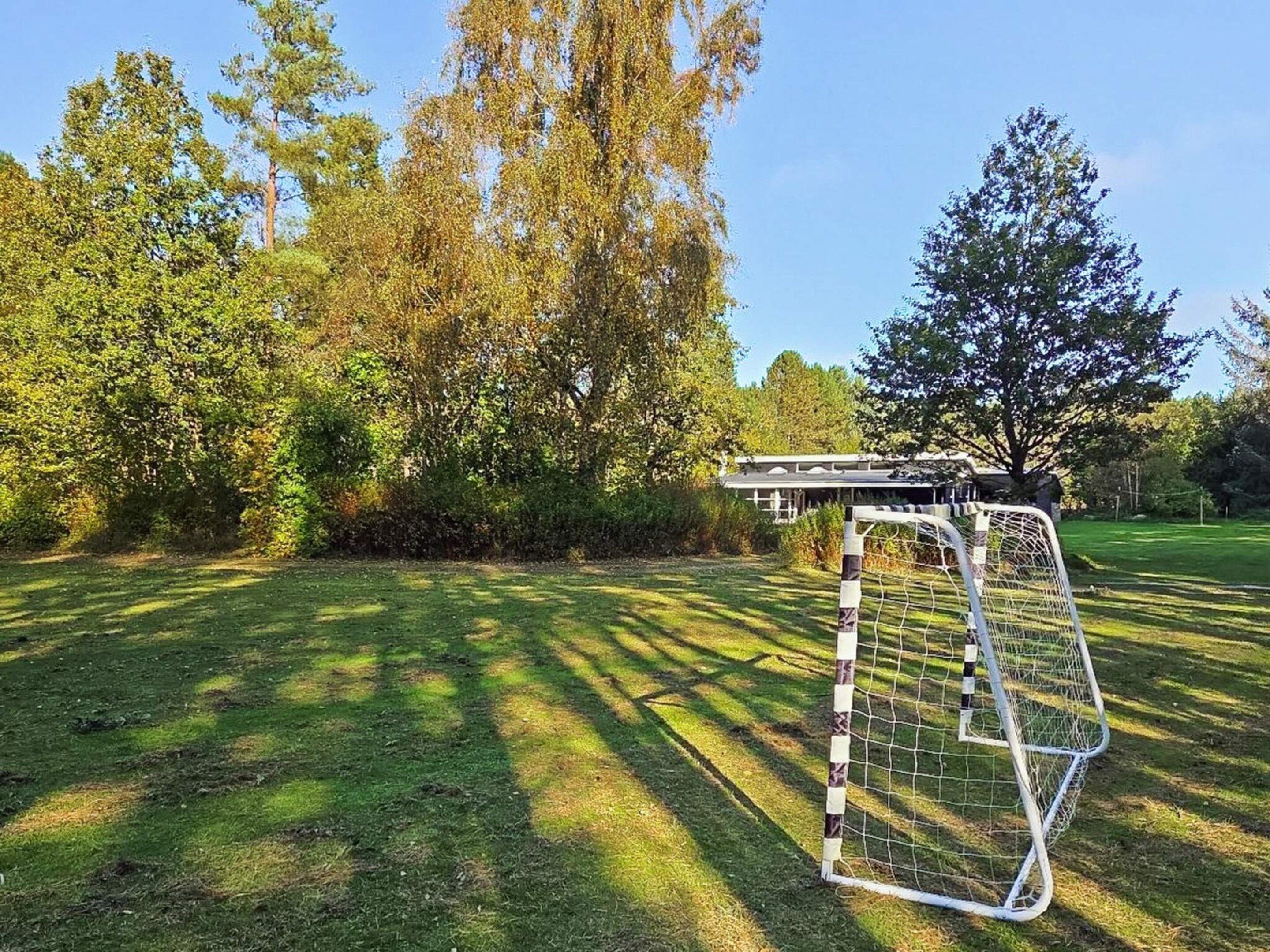 A soccer goal in a grassy area with trees in the background.