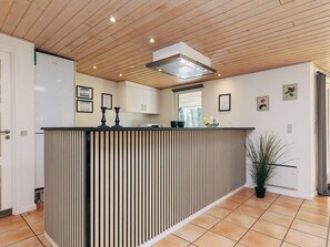 Una cocina moderna con techo de madera, una isla integrada con encimera a rayas negras y blancas, y armarios blancos.
