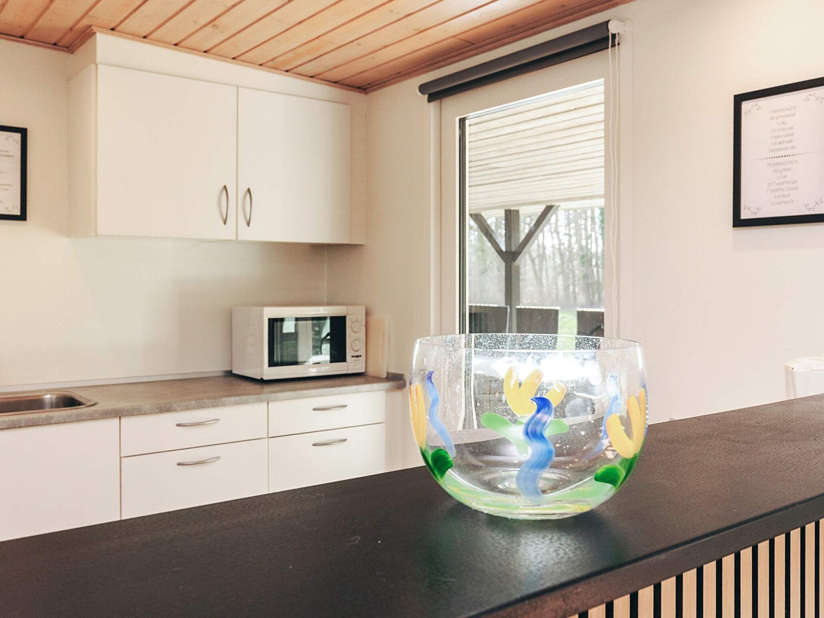 A kitchen with white cabinets, a microwave, and a glass bowl on the counter.
