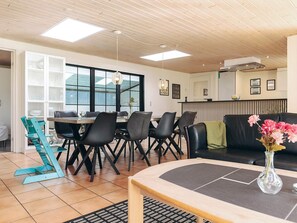 A modern living room with a dining area, featuring a sofa, a coffee table, and a dining table with chairs. - 5 Star Holiday Home in Hals (Asaa)