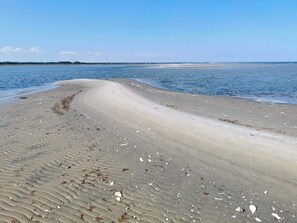 Una playa con un litoral curvo, arena y agua tranquila.