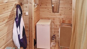 A small, wooden cabin-style room with a bed, a compact kitchenette, and a mirror. - 5 Person Holiday Home in Brekke-by Traum (Gulen)