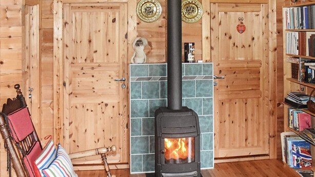 A cozy room with a wood-burning stove, a rocking chair, and a bookshelf. - 5 Person Holiday Home in Brekke-by Traum (Gulen)