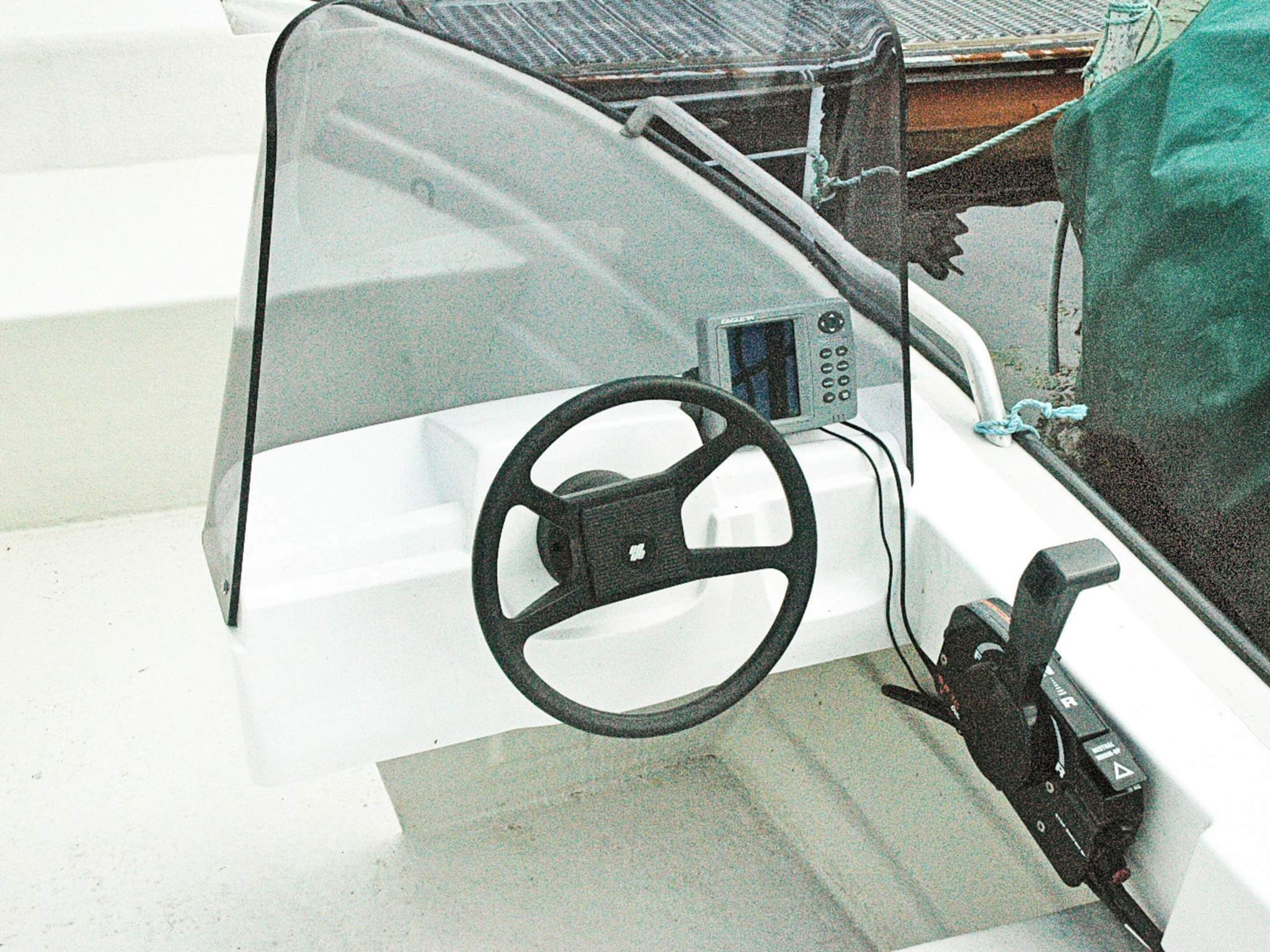 A boat's steering wheel and control panel.