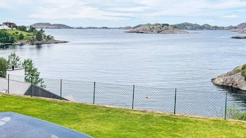 Una propiedad frente al lago con césped vallado, piscina y vistas al agua y a islas distantes.