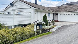 Uma casa branca de dois andares com garagem, chaminé e caixa de correio.