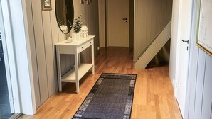 Um corredor com um console branco, um espelho e quadros nas paredes.