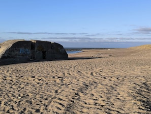 A sandy beach with a concrete structure featuring graffiti.