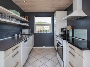 A modern kitchen with white cabinets, a black countertop, a microwave, a coffee maker, and a window with a view.