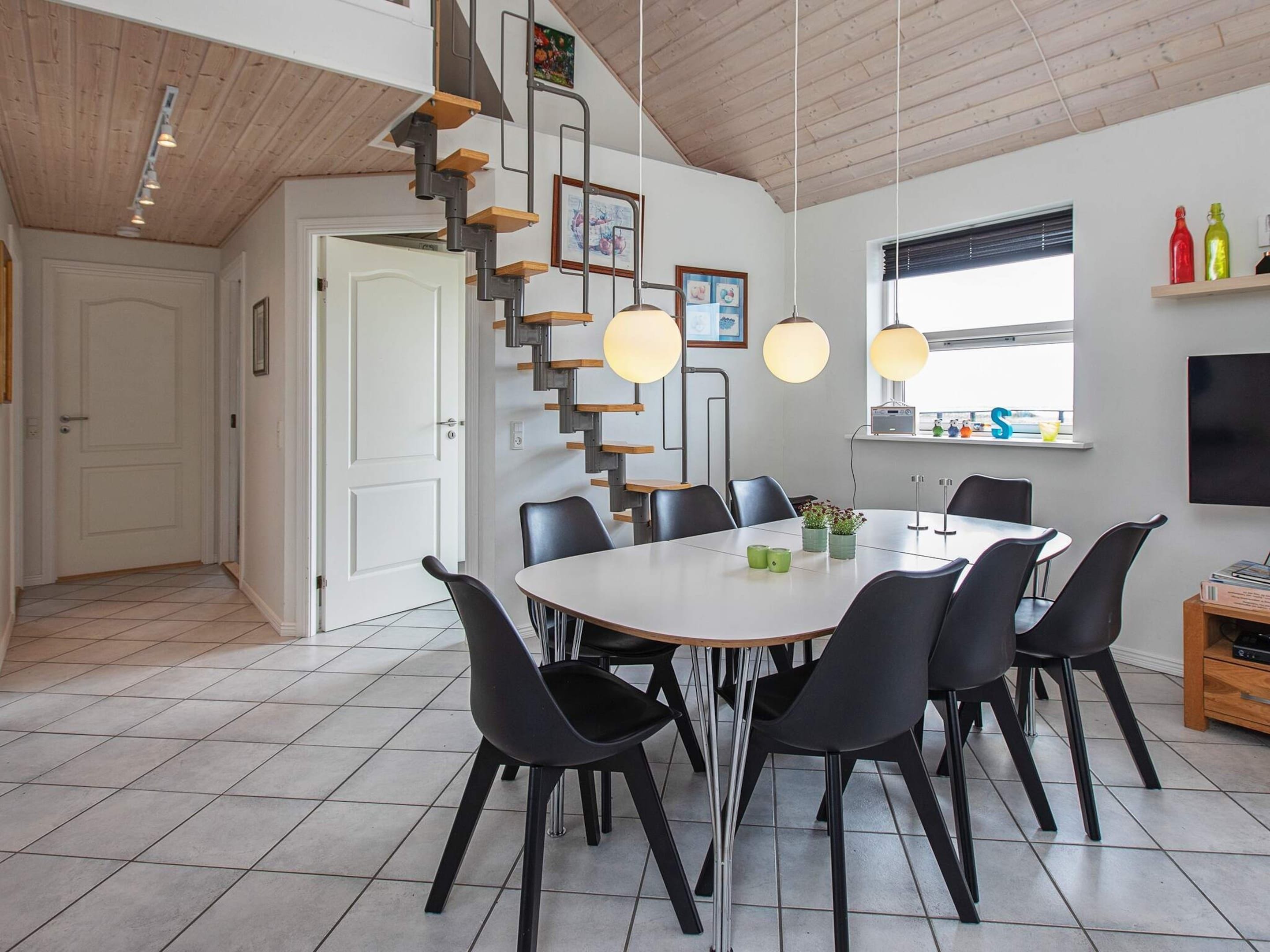 A modern kitchen with a central island, black chairs, and pendant lighting.