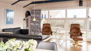 A modern living room with a black sofa, two brown leather chairs, a dining table, and a large window with a view of trees. - 9 Person Holiday Home in Borkop-by Traum (Borkop)
