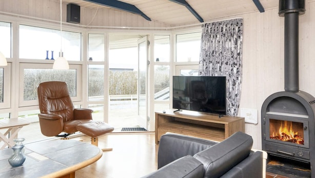 A living room with a TV, leather sofa, and a wood-burning stove. - 9 Person Holiday Home in Borkop-by Traum (Borkop)