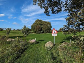 A golf course with a warning sign, trees, and a clear blue sky. - 4 Star Holiday Home in Aabenraa (Aabenraa)