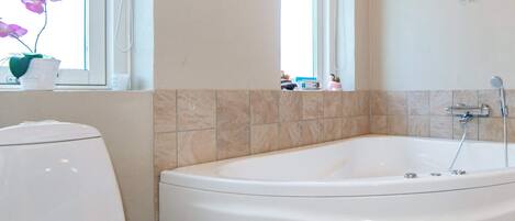 Un baño con bañera, inodoro y ventana con vistas al exterior.