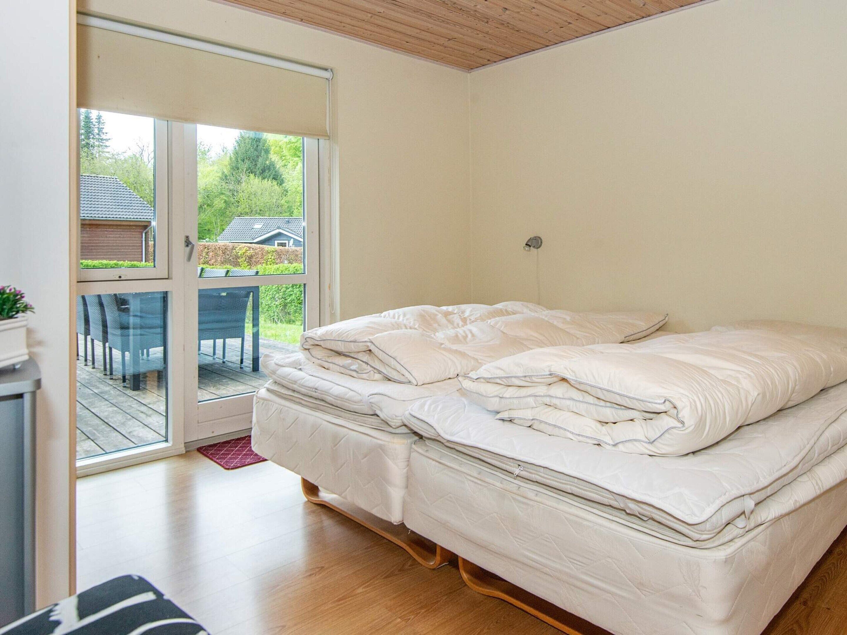 A bedroom with a bed, a sliding glass door leading to an outdoor area, and a small table with chairs.