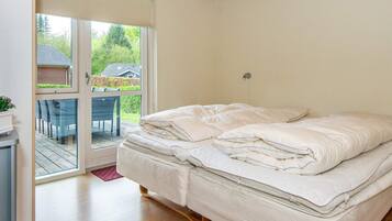 A bedroom with a bed, a sliding glass door leading to an outdoor area, and a small table with chairs.