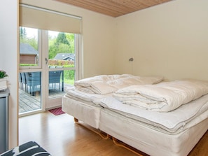 A bedroom with a bed, a sliding glass door leading to an outdoor area, and a small table with chairs. - 4 Star Holiday Home in Aabenraa (Aabenraa)