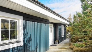 A wooden deck leading to a building with a dark blue exterior and white trim. - Holiday Home in HenÃ¥n (Henån)