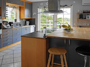 A modern kitchen with grey cabinets, a wooden countertop, a built-in stove, and a window with a view of greenery. - Holiday Home in HenÃ¥n (Henån)