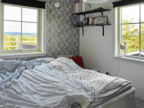 A bedroom with a bed, two windows, a bookshelf, and a view of greenery outside. - Holiday Home in HenÃ¥n (Henån)