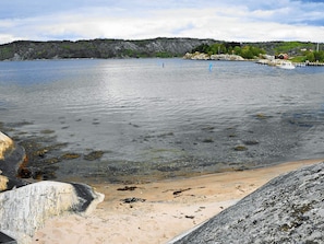 Un lago tranquilo con una playa arenosa y afloramientos rocosos.