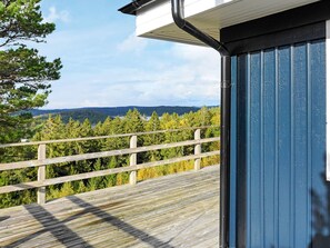 Una terraza de madera con vistas a un bosque y montañas.