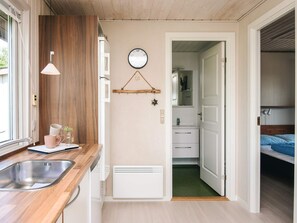 A modern kitchen with a wooden countertop, a built-in sink, and a wall-mounted clock.