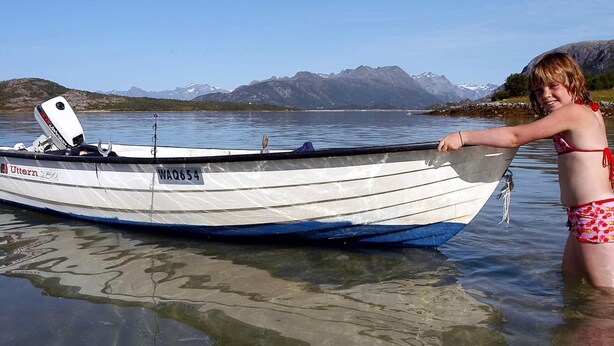 A person in a bikini standing next to a boat with a clear view of mountains in the background. - 6 Person Holiday Home in Engavagen (Meloy)
