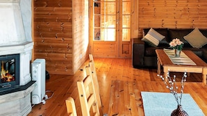 Een gezellig chaletinterieur met een open haard, houten wanden, een bank en een bijzettafeltje.