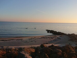 A beach with calm water, two swans, and rocky outcrops. - 4 Star Holiday Home in Rude (Bisserup)