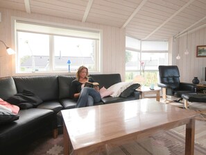 A living room with a black leather sofa, a wooden coffee table, and a black leather chair. - 4 Star Holiday Home in Rude (Bisserup)