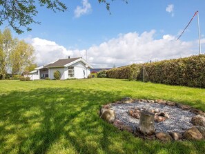 A white house with a satellite dish, surrounded by a well-maintained lawn and a stone border. - 4 Star Holiday Home in Rude (Bisserup)