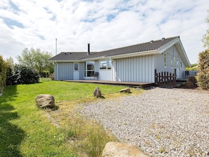 A single-story house with a sloped roof, a front porch, and a gravel driveway. - 4 Star Holiday Home in Rude (Bisserup)