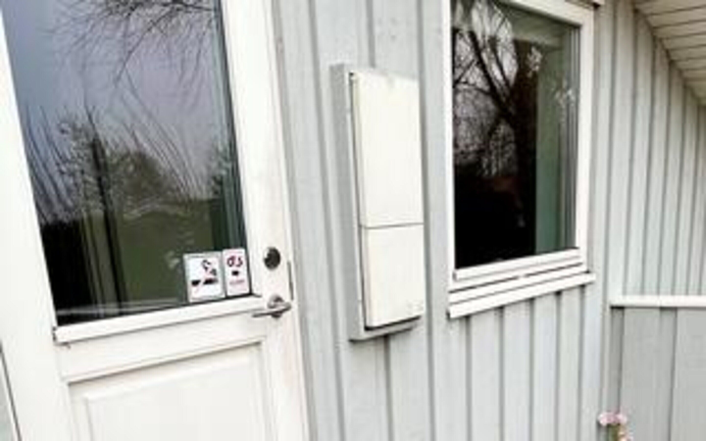 A window with a security lock and a small electronic device attached to the wall.