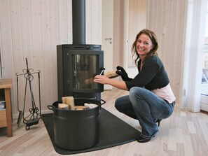 Eine Person bedient einen Holzofen, eine Metallbürste und einen Topf auf einer Matte.